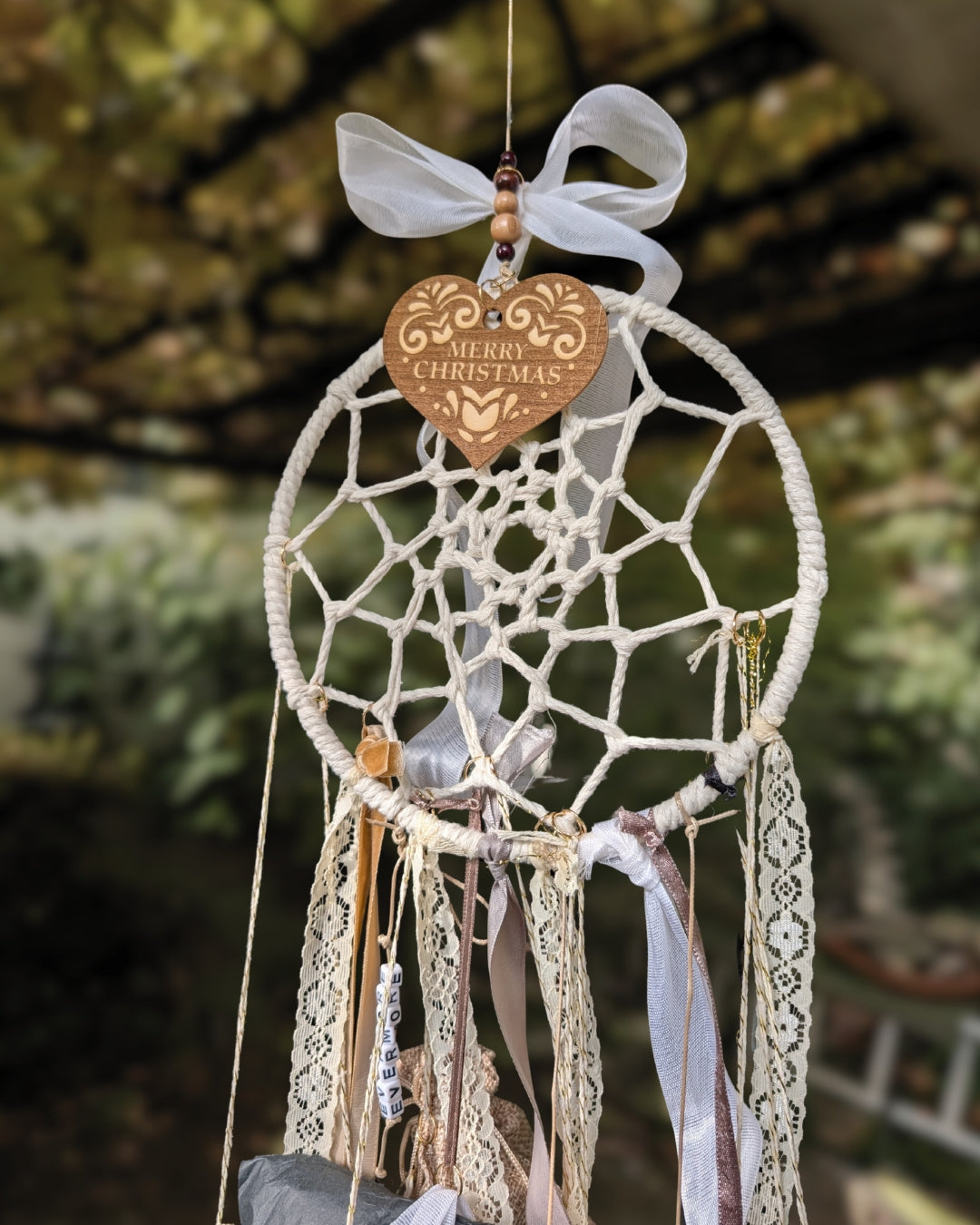 Nahaufnahme des handgemachten Hoggynook Adventskalenders: kleine nummerierte Stoffbeutel am Dreamcatcher, verziert mit Schleifen, Spitze und Satinbändern. Detailshot zeigt hochwertige Handarbeit und rustikale Ästhetik. Perfekte Kombination aus Boho, Dark Academia und Weihnachtsdekoration für Buchliebhaberinnen.