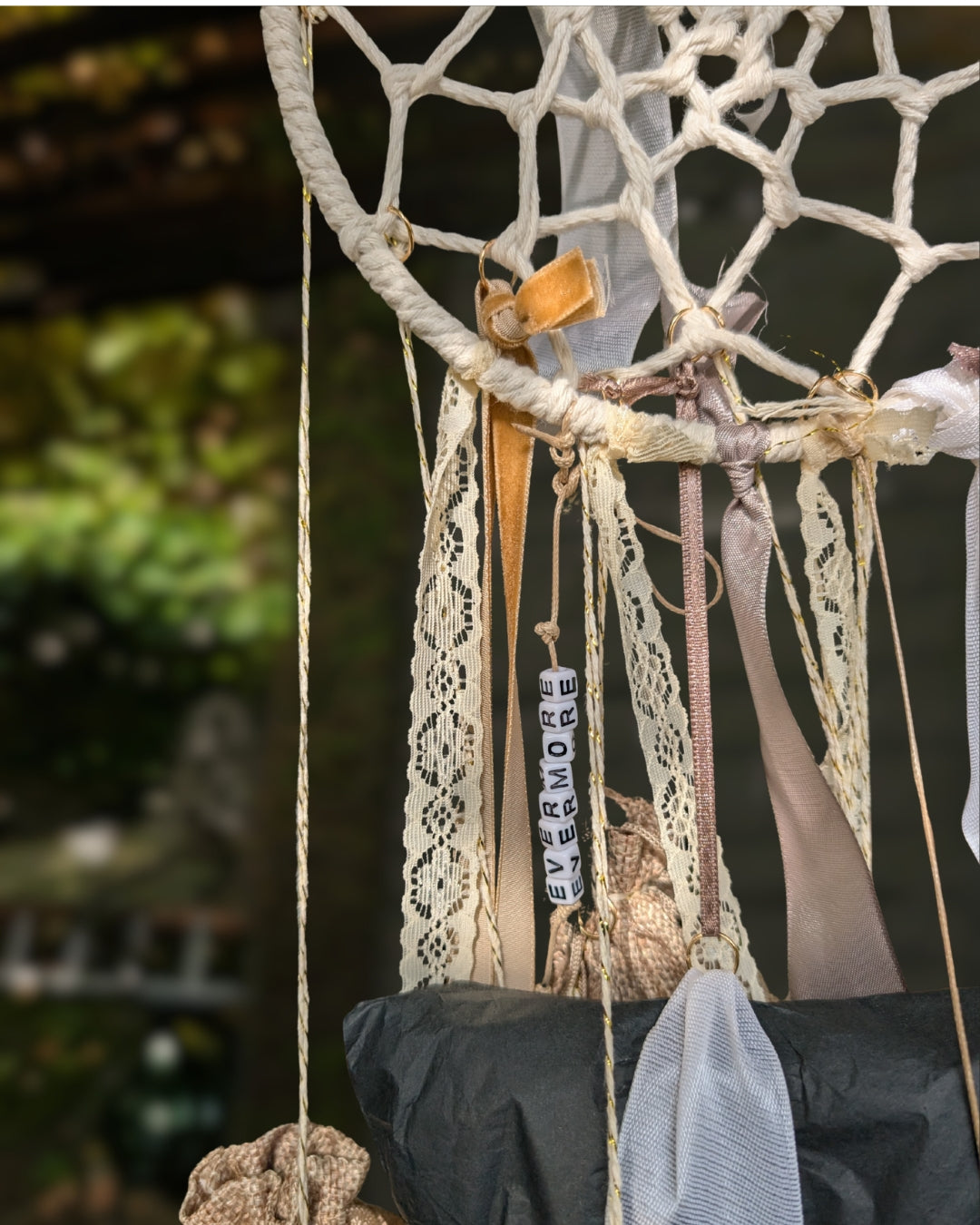 Nahaufnahme des handgemachten Hoggynook Adventskalenders: kleine nummerierte Stoffbeutel am Dreamcatcher, verziert mit Schleifen, Spitze und Satinbändern. Detailshot zeigt hochwertige Handarbeit und rustikale Winter-Ästhetik. Perfekte Kombination aus Boho, Dark Academia und Weihnachtsdekoration für Buchliebhaberinnen.