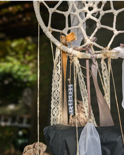 Nahaufnahme des handgemachten Hoggynook Adventskalenders: kleine nummerierte Stoffbeutel am Dreamcatcher, verziert mit Schleifen, Spitze und Satinbändern. Detailshot zeigt hochwertige Handarbeit und rustikale Winter-Ästhetik. Perfekte Kombination aus Boho, Dark Academia und Weihnachtsdekoration für Buchliebhaberinnen.